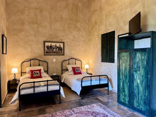 a bedroom with two beds and a tv on the wall at Loft El Tapatío en Val'Quirico in Santeagueda