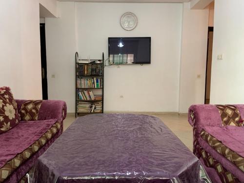 uma sala de estar com dois sofás roxos e uma televisão em Bel appartement au calme, proche du centre ville em Kenitra