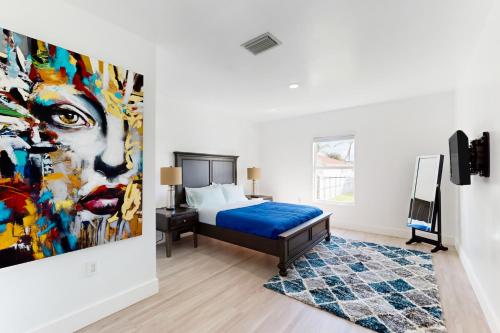 哈蘭代爾海灘的住宿－Hallandale Haven，卧室配有一张床,墙上挂有绘画作品