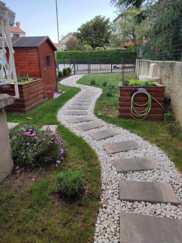 a garden with a stone walkway and a house at Apartma VitaMia in Ankaran