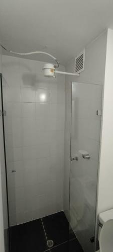 a white bathroom with a shower and a toilet at Hotel Paradise Lleras in Medellín