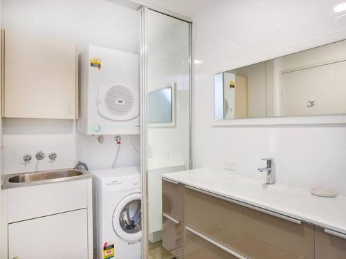 a white bathroom with a washing machine and a sink at Maimi renovated 2-bedroom apartment in Gold Coast