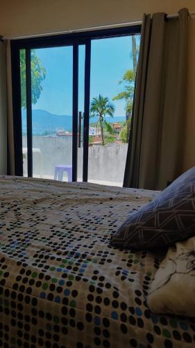 a bedroom with a bed with a view of the beach at Quarto vista mar São Sebastião in São Sebastião