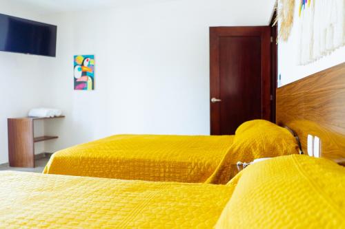 two beds with yellow covers in a room at Santa Martha Bungalows in Los Ayala