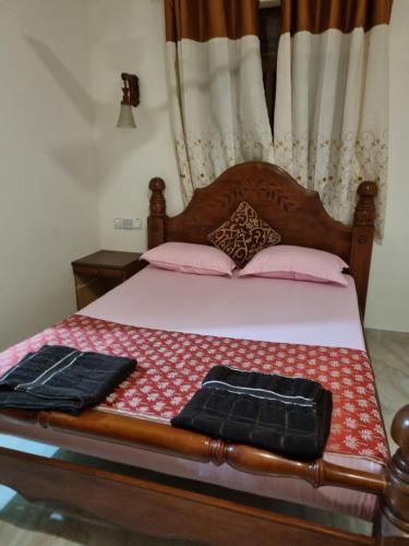a bed with a wooden head board with pink pillows at JAYANDRA HOLIDAY BUNGALOW in Waga