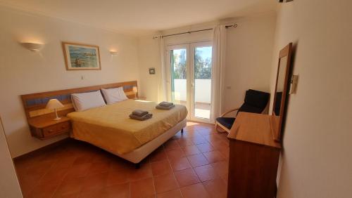 Casa Amarela في تافيرا: غرفة نوم بسرير وكرسي ونافذة