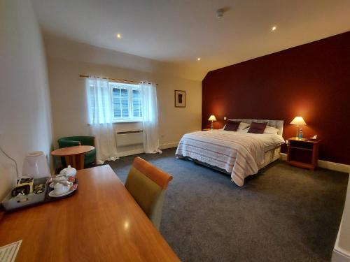 a bedroom with a bed and a table and a desk at The Coach and Horses in Winchester