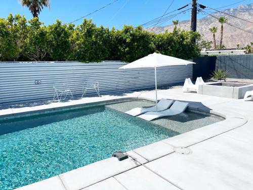 a swimming pool with an umbrella and two lounge chairs and an umbrella at Super Cute room in Architectural Home in Palm Springs