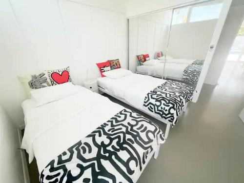 two beds with black and white sheets in a room at Super Cute room in Architectural Home in Palm Springs