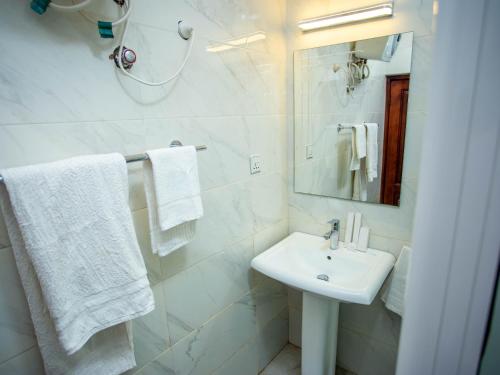 a white bathroom with a sink and a mirror at Royal N Hotel in Accra