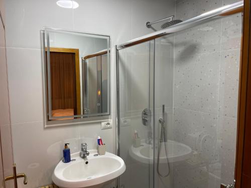 ein weißes Bad mit einem Waschbecken und einer Dusche in der Unterkunft Cozy Apartment, in the center of Tirana in Tirana
