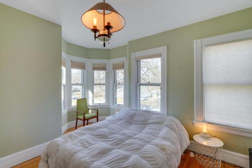 a bedroom with a bed and two windows and a chandelier at Pet-Friendly Hudson Home Near Won Dharma Center! in Hudson