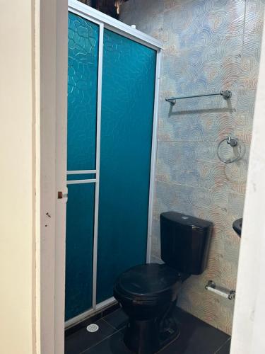 een badkamer met een zwart toilet en een blauwe muur bij Punta Arena EcoHostal & EcoFit - Your Eco-Friendly Oasis in Playa Punta Arena