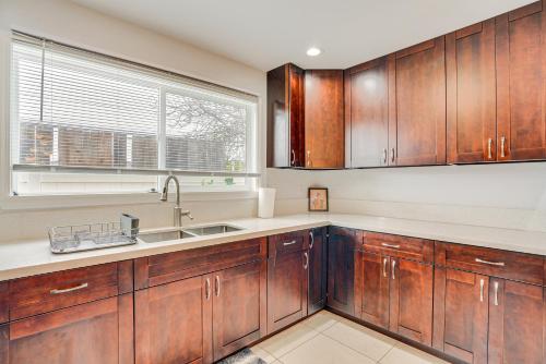 a kitchen with wooden cabinets and a window at Pet-Friendly Ewa Beach Apartment about 1 Mi to Ocean! in Kapolei