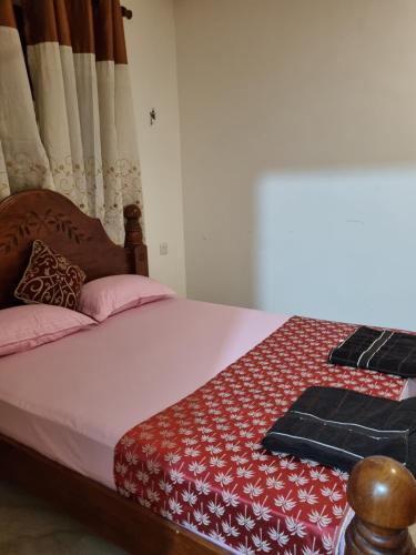 a bedroom with a bed with a red and white quilt at JAYANDRA HOLIDAY BUNGALOW in Waga