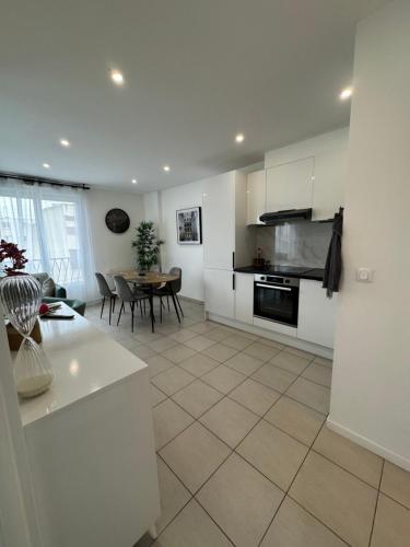 une cuisine avec des armoires blanches et une table avec des chaises dans l'établissement Appartement 2 Chambre (Proche centre ville), à Drancy