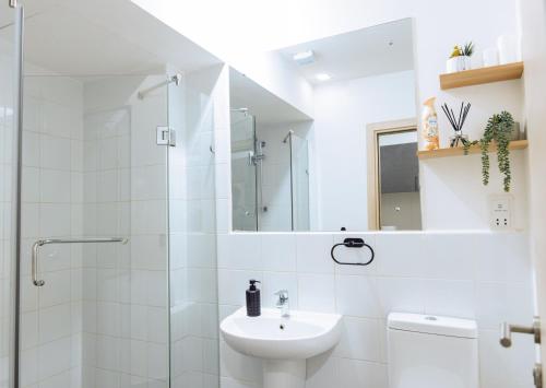 a white bathroom with a sink and a shower at Luxury Studio Suite at The Gallery in Accra