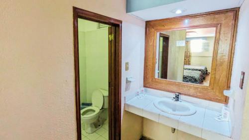 a bathroom with a sink and a toilet and a mirror at Hotel Plaza San Juan in Mexico City