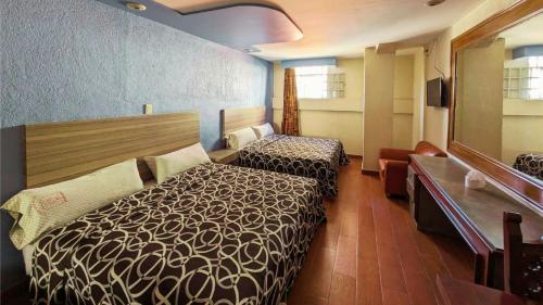 メキシコシティにあるHotel Plaza San Juanのベッド2台と鏡が備わるホテルルームです。