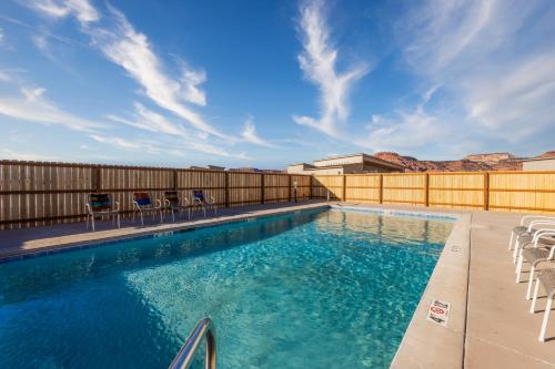 a large swimming pool with chairs and a fence at High Desert luxury with views for families in Kanab