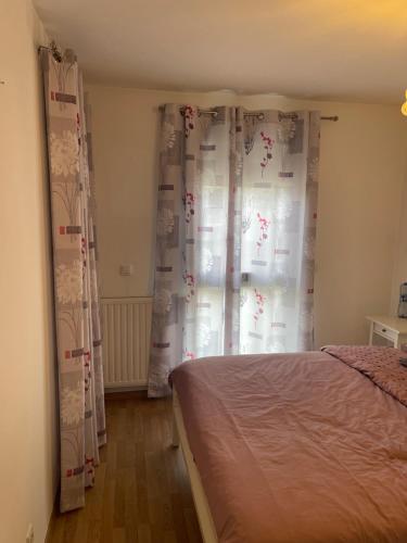 um quarto com uma cama e uma janela com cortinas em Cerisier em Ségny