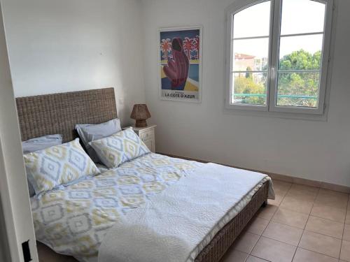 ein Schlafzimmer mit einem Bett und zwei Fenstern in der Unterkunft Charmante Maison T3 Parking, Clim, Front de Mer in Grimaud