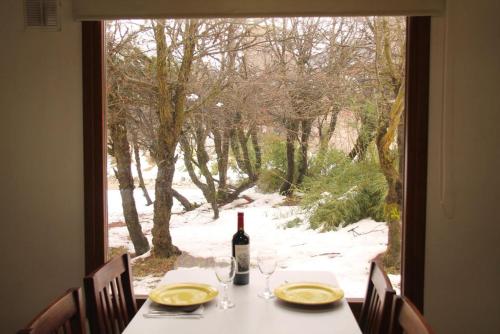 una mesa con una botella de vino y una ventana en Departamento Base Cerro Catedral en San Carlos de Bariloche