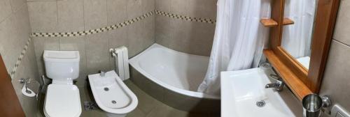 y baño con aseo, bañera y lavamanos. en Departamento Base Cerro Catedral en San Carlos de Bariloche