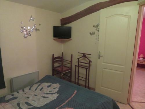 une chambre avec un lit et une télévision au mur dans l'établissement Gite Les hippocampes, à Saint-Germain-de-Marencennes