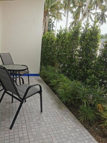 a patio with two chairs and a table and plants at NST Boutique เอ็นเอสทีบูทีค in Ban Pak Phun