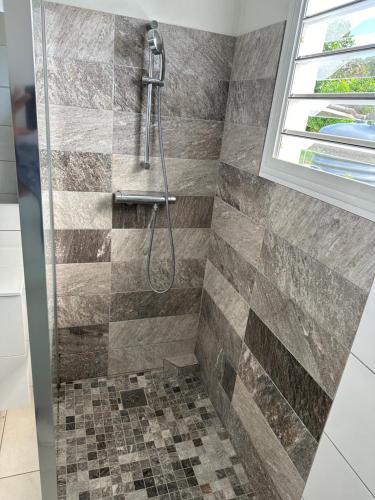 a shower with a shower head in a bathroom at Kama in Sainte-Luce