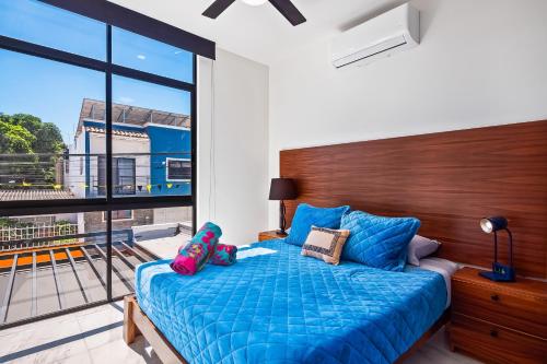 sypialnia z niebieskim łóżkiem i dużym oknem w obiekcie Coastal Comfort Haven w mieście Nuevo Vallarta
