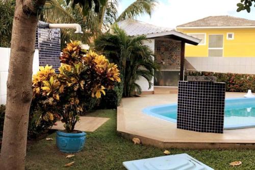 una casa con piscina e una palma di CASA DE PRAIA NO CONDOMÍNIO PARAÍSO, GUARAJUBA a Camassari
