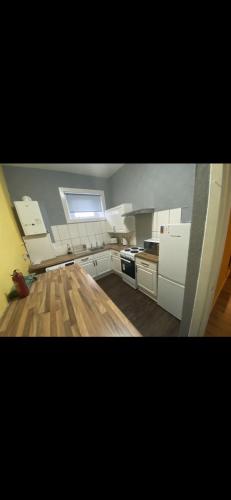 een keuken met witte kasten en een houten vloer bij Town centre apartment in Motherwell