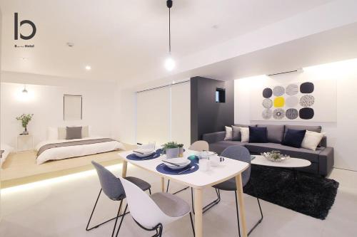 a living room with a couch and a table and chairs at b hotel Heiwaodori 202 - New Apt Famous Hiroshima Hondori for 6p in Hiroshima