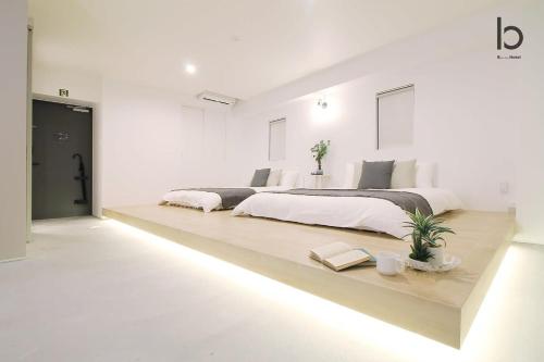 a white bedroom with two beds and a table at b hotel Heiwaodori 202 - New Apt Famous Hiroshima Hondori for 6p in Hiroshima