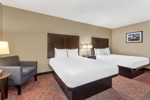 a hotel room with two beds and a chair at Best Western Airport Inn & Suites in Charleston