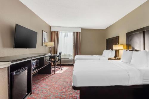 a hotel room with two beds and a flat screen tv at Best Western Airport Inn & Suites in Charleston