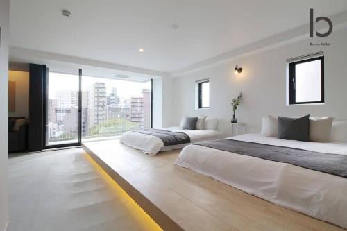 biała sypialnia z 2 łóżkami i dużym oknem w obiekcie bHOTEL Heiwaoodori 601 - New Apt In Famous Hiroshima Dori For 6p w mieście Hiroszima