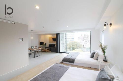 a white bedroom with a bed and a living room at b hotel Heiwaodori 601 - New Apt In Famous Hiroshima Dori For 6p in Hiroshima
