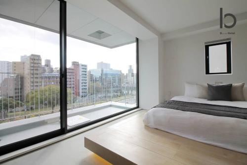 a bedroom with a large bed and a large window at b hotel Heiwaodori 601 - New Apt In Famous Hiroshima Dori For 6p in Hiroshima