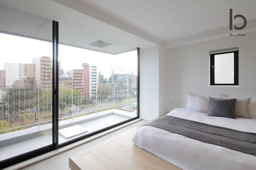 a white bedroom with a large window and a bed at b hotel Heiwaodori 601 - New Apt In Famous Hiroshima Dori For 6p in Hiroshima