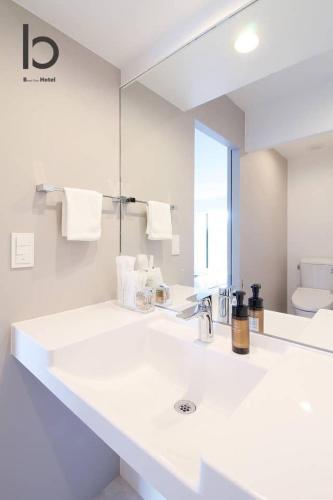 a white bathroom with a sink and a mirror at b hotel Heiwaodori 601 - New Apt In Famous Hiroshima Dori For 6p in Hiroshima