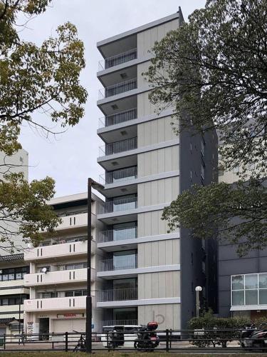 a tall building with a parking lot in front of it at b hotel Heiwaodori 601 - New Apt In Famous Hiroshima Dori For 6p in Hiroshima