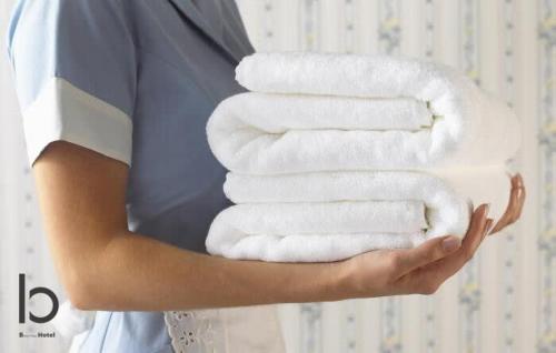 a woman holding a stack of white towels at b hotel Heiwaodori 701 - Spacious Apt Famous Hiroshima Dori 6ppl in Hiroshima