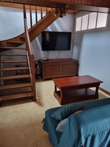 ein Wohnzimmer mit einem TV, einem Tisch und einem Sofa in der Unterkunft Maison de famille in Pré-en-Pail