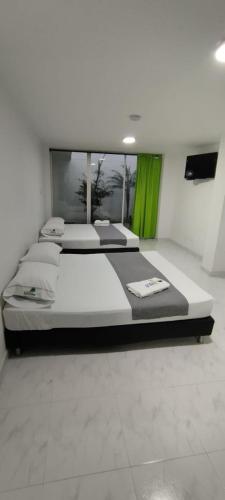 two beds in a room with green curtains at Hotel Paradise Lleras in Medellín