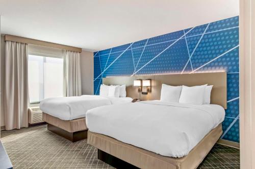 una camera d'albergo con due letti e una parete blu di Comfort Suites Whitsett a Whitsett
