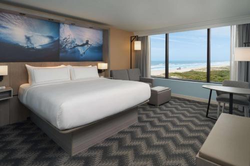 a hotel room with a large bed and a desk at Hilton Cocoa Beach Oceanfront in Cocoa Beach