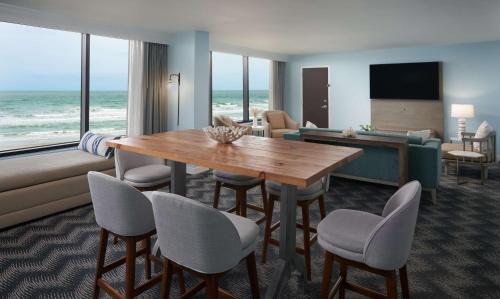 une chambre d'hôtel avec une table et des chaises et l'océan dans l'établissement Hilton Cocoa Beach Oceanfront, à Cocoa Beach